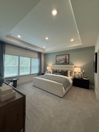 A serene bedroom featuring a cozy bed, large windows, soft carpet, and elegant decor. Perfect for relaxation and comfort.