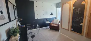 A modern study room featuring geometric wall art, clear chairs, and a cozy reading nook with a leather armchair.