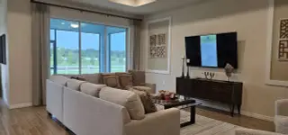 A cozy living room featuring a plush sectional sofa, large windows with scenic views, and elegant wall decor.