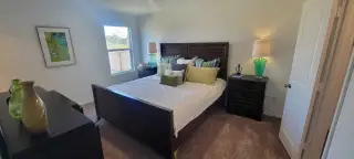 A cozy bedroom featuring a dark wood bed, vibrant pillows, stylish lamps, and wall art for a touch of color.