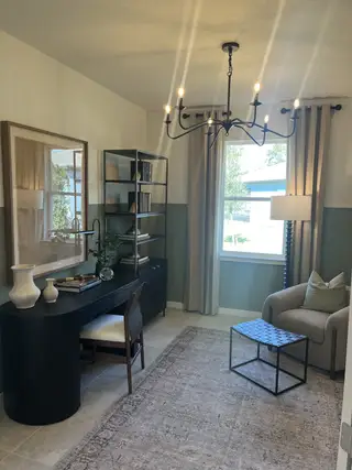 A sophisticated home office with a modern chandelier, elegant desk, and cozy seating area.