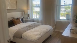 A cozy bedroom featuring a plush bed, soft neutral tones, large windows, and modern decor.