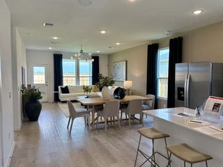 Model Home A modern, open-concept living area with sleek furniture, large windows, and a cozy dining setup.