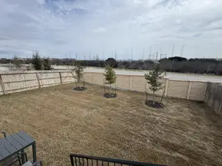 Street view A spacious backyard with young trees and a privacy fence in Hunters Ranch - The Meadows by View Homes (San Antonio, TX).