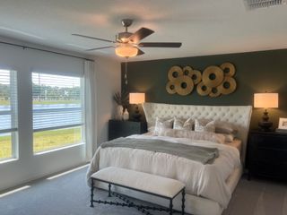 A serene bedroom with a tufted bed, artistic wall decor, cozy lighting, and a window overlooking a beautiful outdoor view.