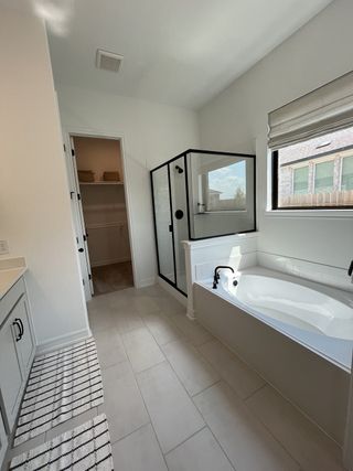 A modern bathroom featuring a sleek glass shower, relaxing bathtub, and ample closet space.