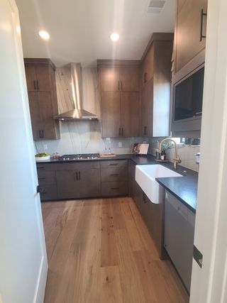 A modern kitchen with sleek brown cabinets, a farmhouse sink, and stainless steel appliances.