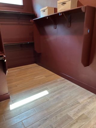 Model Home A spacious closet with rich brown walls, wooden flooring, and ample shelving for storage.