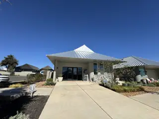 A modern home with a sleek metal roof and manicured landscaping in Wolf Ranch: Genesis Collection by Lennar (Georgetown, TX).
