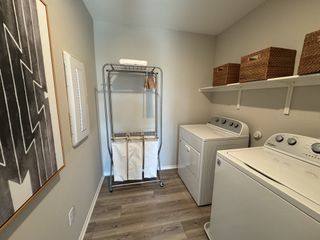 A functional laundry room with a washer, dryer, shelving, and stylish wall art.