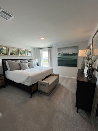 Elegant bedroom with a plush bed, modern decor, and serene art, creating a cozy and inviting atmosphere.