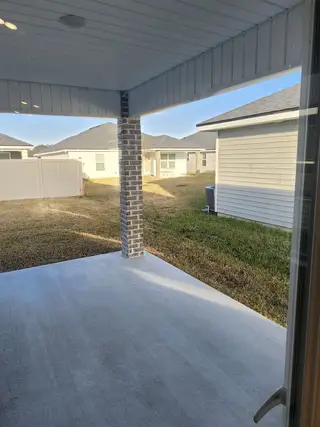 A peaceful covered porch leading to the spacious backyard, ideal for relaxation or entertaining.