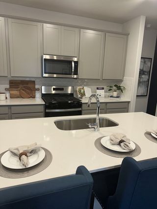 Model Home A modern kitchen with a sleek island, stainless steel appliances, and elegant cabinetry.