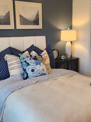 Cozy bedroom featuring a tufted headboard, patterned pillows, ambient lighting, and elegant wall art.