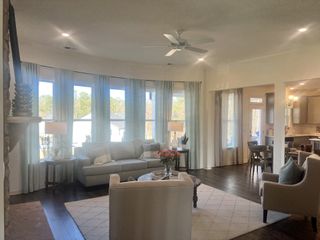 Model Home A cozy, sunlit living room with elegant curtains, plush seating, and rich wooden floors complement an open, inviting layout.
