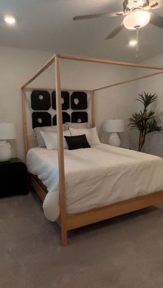 Model Home A cozy bedroom with a modern canopy bed, elegant black and white accents, and soft lighting.