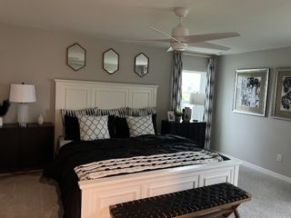A modern bedroom with a white bed frame, geometric pillows, and stylish monochrome decor.
