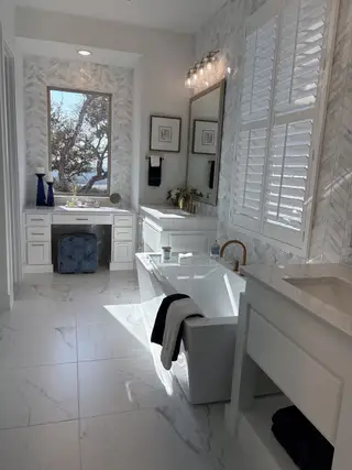 Model Home A luxurious bathroom featuring a sleek bathtub, herringbone marble walls, and elegant lighting with scenic views.