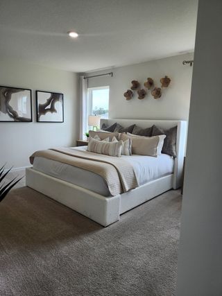 A cozy bedroom with a plush bed, neutral decor, and modern art creating a relaxing ambiance.