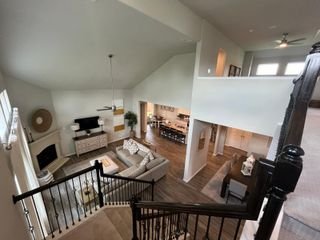 A spacious open-concept living area with a vaulted ceiling, elegant staircase, and cozy fireplace.