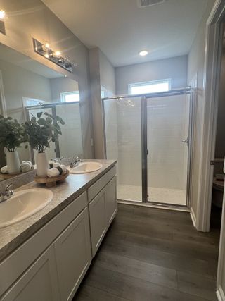 A modern bathroom featuring a double sink vanity, sleek lighting, and a glass-enclosed shower.