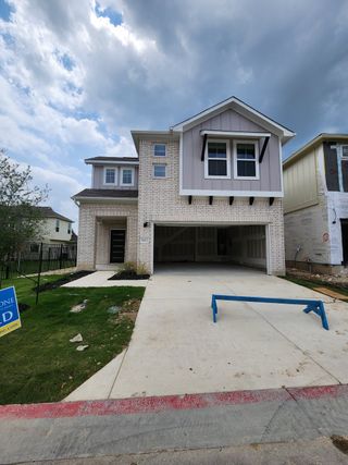 Street view A charming two-story home with white brick and a spacious driveway in Messinger Village by Milestone Community Builders (Austin, TX).