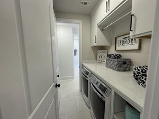 Model Home A sleek laundry room featuring modern appliances, ample storage, and tasteful decor on a pristine white countertop.