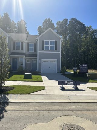 Street view A charming gray townhome with black shutters and a lush yard in Cavastead Townhomes by Ryan Homes (Raleigh, NC).