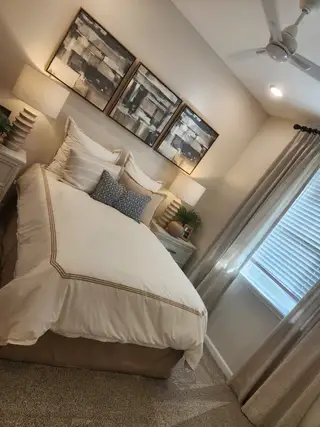 A cozy bedroom with elegant bedding, abstract wall art, and soft lighting creates a serene atmosphere.