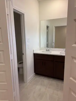 A modern bathroom featuring a sleek vanity, large mirror, and elegant tile flooring.