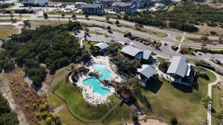 Community Amenities A breathtaking aerial view of the Headwaters community, showcasing an infinity-edge pool, scenic trails, and lush green spaces in Headwaters by David Weekley Homes (Dripping Springs, TX).
