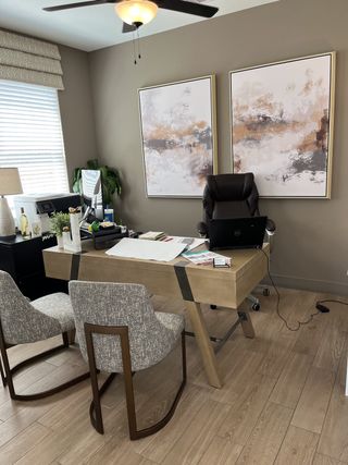 A modern office with abstract art, wooden desk, and comfortable seating, featuring warm tones and sleek decor.