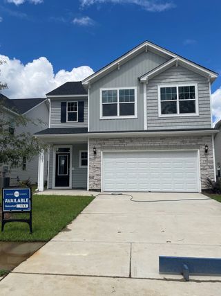 A charming two-story home with gray siding and a white garage in Six Oaks by Mungo Homes, Summerville, SC.
