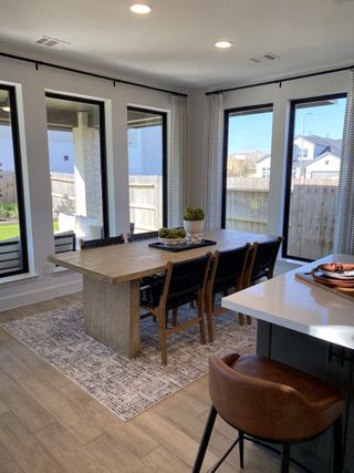 A modern dining area with a rustic wooden table, cozy chairs, and floor-to-ceiling windows overlooking the yard.