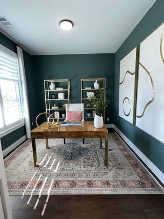 A stylish home office with deep green walls, gold shelving, and elegant décor.