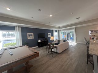An inviting living space with a pool table, navy accent wall, elegant lighting, and sliding glass doors leading to a patio.