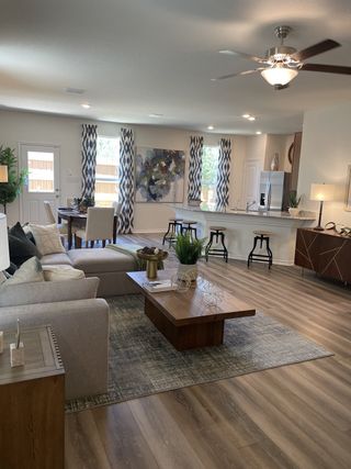 A bright and spacious living area in a Villas at Presidio home, featuring a comfortable gray sofa, a wooden coffee table, and an open layout leading to the dining area and kitchen (San Antonio, TX).