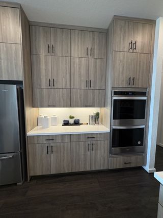 Model Home An open-concept kitchen with a waterfall island, integrated microwave, and dark wood flooring in Esperanza by Scott Felder Homes (Boerne, TX).