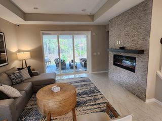 A cozy living room with a sleek tiled fireplace, plush sofa, and large glass doors leading to a serene outdoor view.