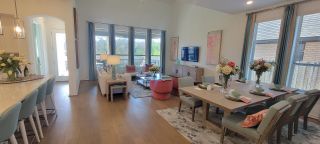 Model Home A bright, open-concept living and dining area with hardwood floors, large windows, and tasteful decor flows seamlessly for modern living.