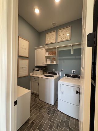 A chic laundry room featuring a sleek washer and dryer, elegant cabinetry, and stylish decor with ample lighting.