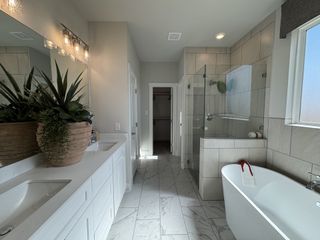 Model Home A modern bathroom with a freestanding tub, glass shower, dual sinks, and chic lighting.