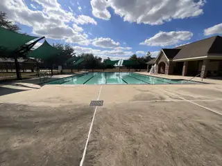 A beautiful community pool with shaded seating and a clubhouse in Cypresswood Point by Long Lake Ltd. (Humble, TX).