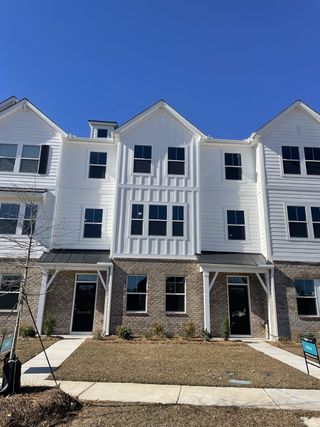Street view Modern three-story townhouse in Village Club at Wescott by Ashton Woods, featuring brick and siding façade (Summerville, SC).