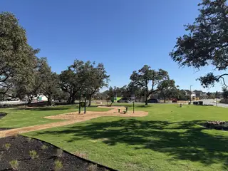 Lush community park with mature trees and benches in Parkside on the River by Coventry Homes (Georgetown, TX).