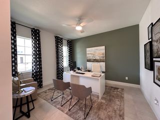 A modern home office featuring a sleek white desk, elegant artwork, and stylish curtains with a calming green accent wall.