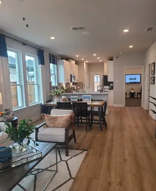 Model Home A modern open-concept kitchen and dining area with wood floors, cozy seating, and abundant natural light.