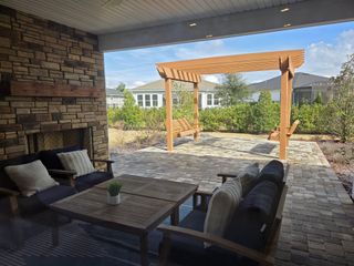 A cozy patio with a stone fireplace, pergola swing, and comfortable seating, perfect for outdoor relaxation.