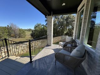 Model Home A serene patio with comfy seating, sleek railing, and scenic nature views for perfect relaxation.