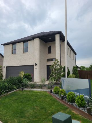 Street view A modern two-story white brick home with sleek landscaping in Eastridge by Trophy Signature Homes (McKinney, TX).
